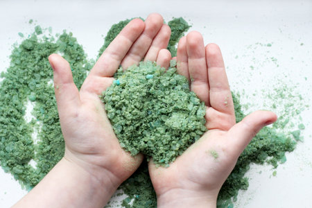 Green sea salt in the child hands top viewの写真素材