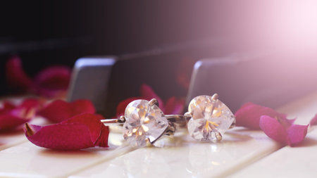 Piano keys with rose petals and earrings on a black background