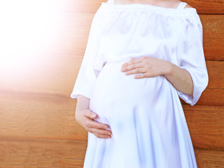 Pregnant woman in white dress on wooden background, closeupの写真素材