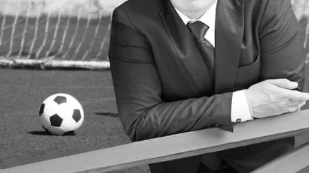 Businessman with soccer ball on the football field, black and whiteの写真素材