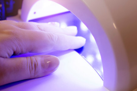 A woman's hand with a manicure is dried in an ultraviolet lamp