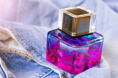 Women's pink-lilac perfume and blue jeansの写真素材