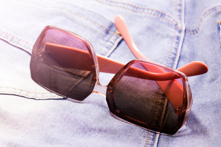 Women's pink square-rimmed glasses and blue jeansの写真素材