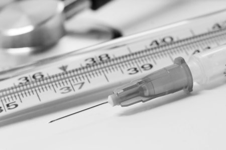Medical syringe and stethoscope on a white background.