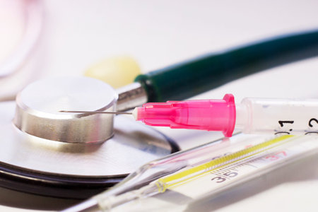 Stethoscope, syringe and pills on a white background.