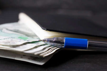 Money and pen on black background, close-up. Business conceptの写真素材
