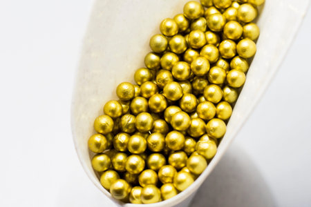 golden beads in a cup on a white background, close-upの写真素材