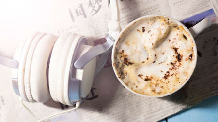 Cappuccino cup, large headphones and Chinese newspaperの写真素材