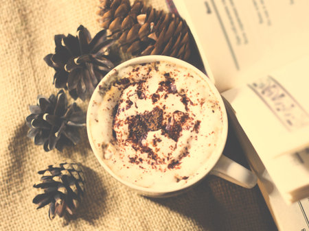 Cappuccino with cinnamon and pine cones on a burlap backgroundの写真素材