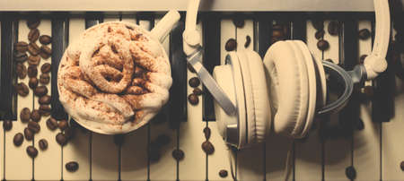 Cup of coffee with cookies and headphones on piano, closeupの写真素材