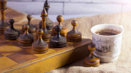 Wooden chessboard with chess pieces and a cup of coffee on the tableの写真素材