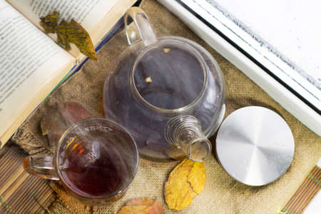 Glass teapot with tea and yellow autumn leaves, vintageの写真素材