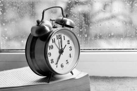 Alarm clock and book on the windowsill. Black and whiteの写真素材