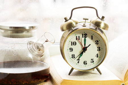 Alarm clock and teapot on the background of the window