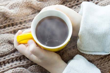 Yellow mug in children's hands so closeの写真素材
