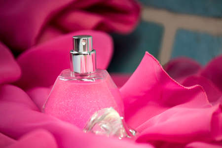 Women's perfume on pink fabric, brick backgroundの写真素材