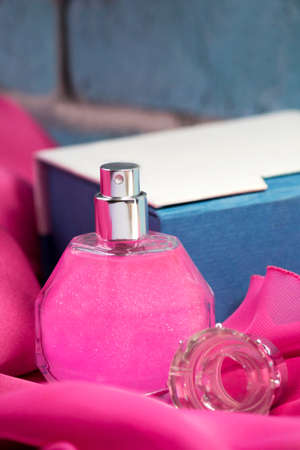 Women's perfume on pink fabric, brick backgroundの写真素材