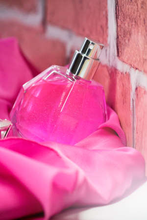 Women's perfume on pink fabric, brick backgroundの写真素材