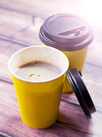 Two yellow paper cups of coffee on a wooden tableの写真素材