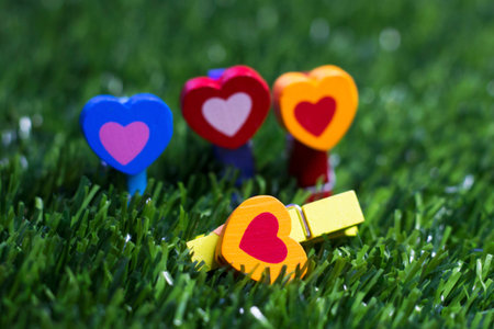 Colored wooden clothespins with hearts on the grass so close