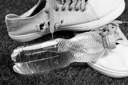 Sneakers and bottle of water on green grass, black and whiteの写真素材