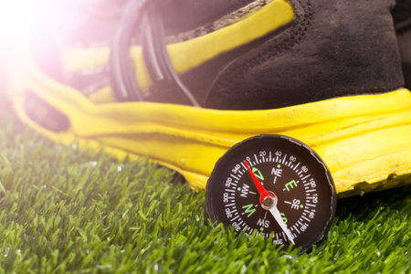 Compass and yellow sneakers on the grass