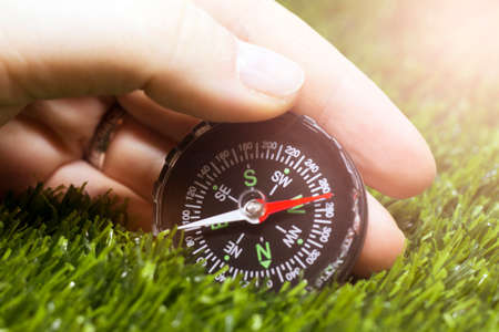 Compass in hand on green grass background. Travel and adventure conceptの写真素材
