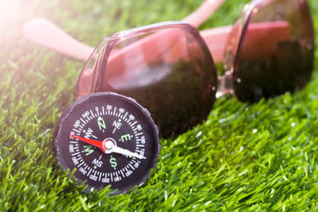 Compass and sunglasses on green grass, closeup. Travel conceptの写真素材