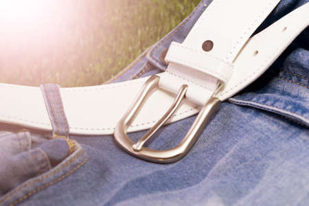 Men's jeans with white leather belt on the green grass background.の写真素材