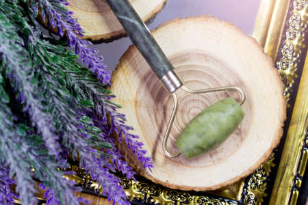 Jade roller for face massage on a wooden background with lavender.の写真素材