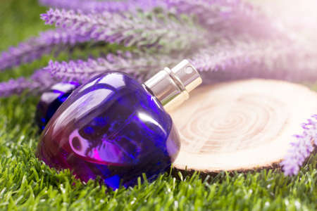 Perfume bottle with lavender flowers on green grass background.の写真素材