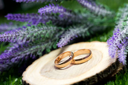 Wedding rings on a sawn tree and a bouquet of lavenderの写真素材