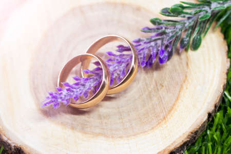 Wedding rings on a sawn tree and a bouquet of lavenderの写真素材