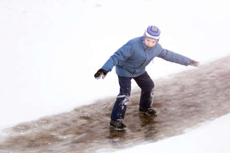 Funny boy rides down an ice slide, winterの写真素材