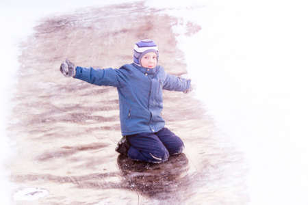 Funny boy rides down an ice slide, winter funの写真素材