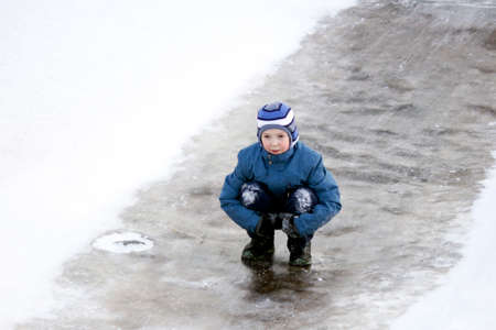 Funny boy rides down an ice slide, winter funの写真素材