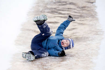 Funny boy rides down an ice slide, winter funの写真素材