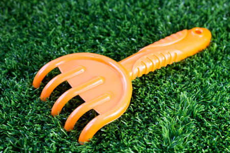 Orange children's rake on the grassの写真素材