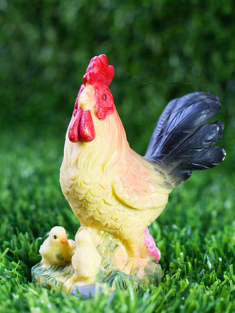 A rooster figurine with chickens in the grass