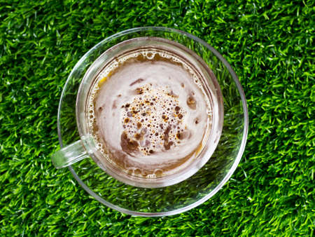 Coffee in a glass cup and saucer on the grass in the gardenの写真素材