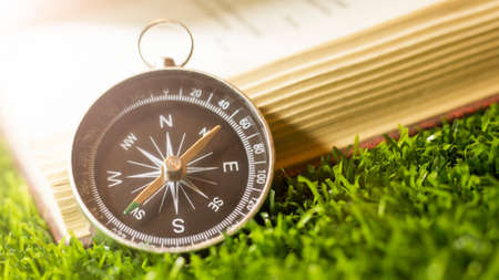 Retro compass and book on the grass, summer tripの写真素材