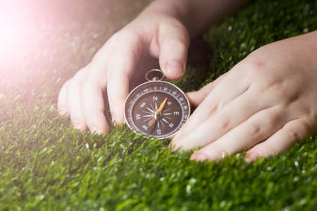 Retro compass in children's hands on the grassの写真素材