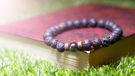 A bracelet made of black beads and a book on the grass, an amulet made of natural stonesの写真素材
