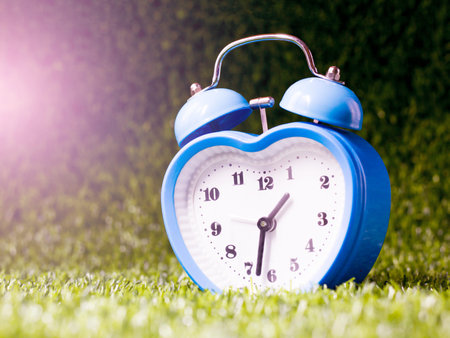 Blue alarm clock heart shape on the grass