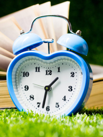 Alarm clock on green grass with books. Time to study.の写真素材