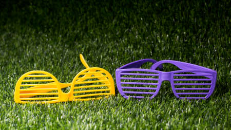 Yellow and purple children's plastic glasses on the grass, toys for childrenの写真素材