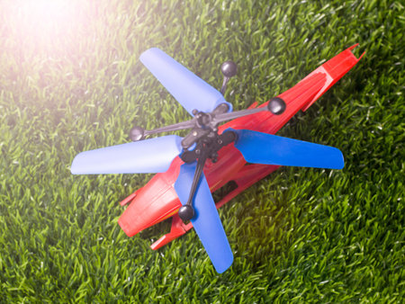Plastic toy helicopter on green grass background. Close-up.