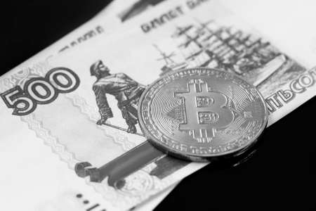 Bitcoin coin on the background of dollar bills. Black and white photo.の写真素材