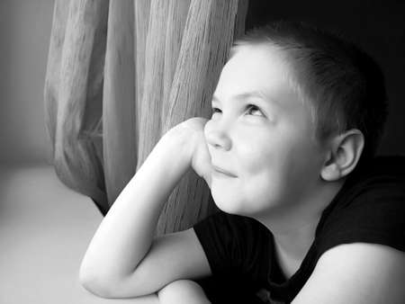 A happy boy looks out the window, a child's portraitの写真素材