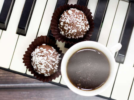Chocolate cake with coconut and a cup of coffee on the pianoの写真素材